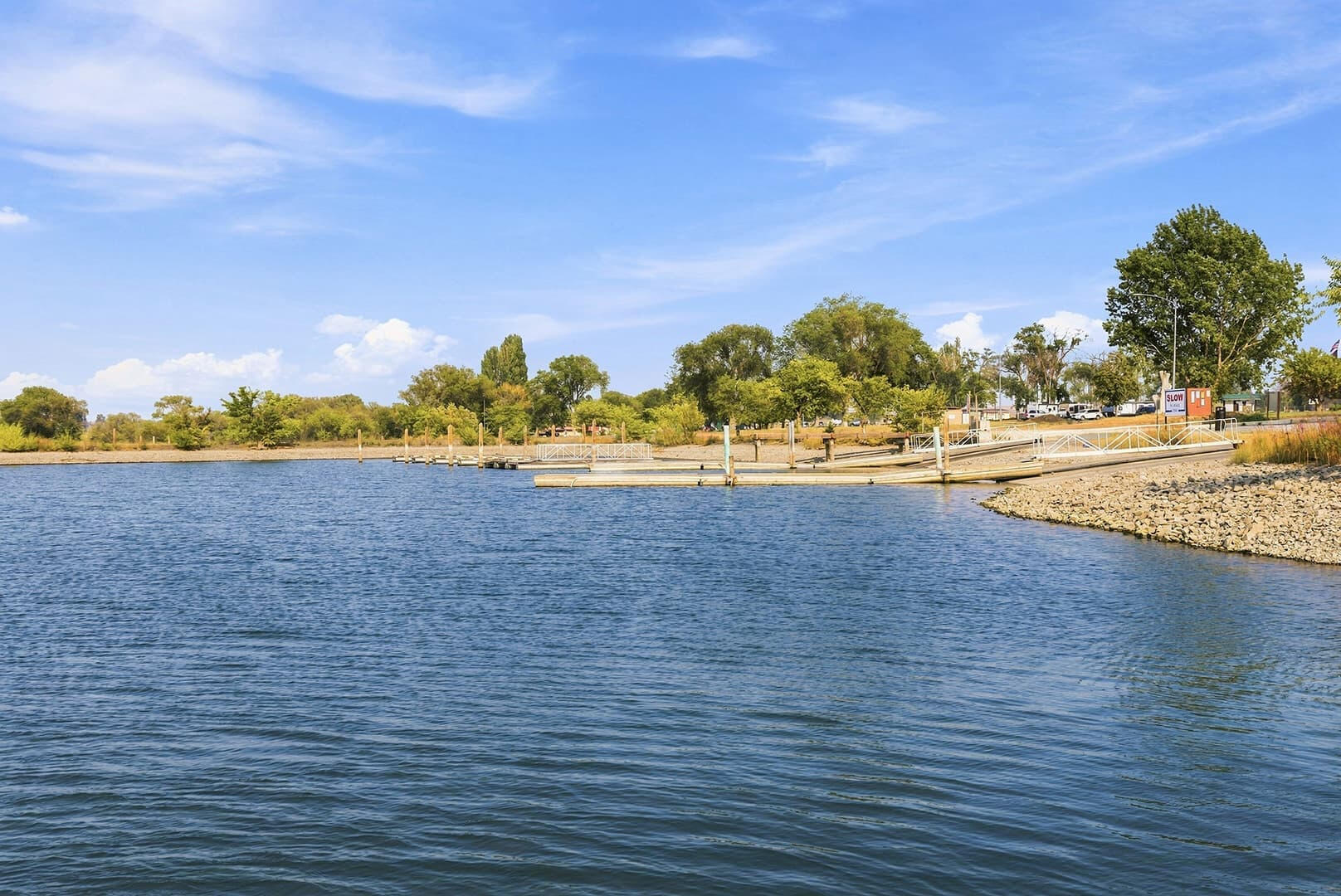 View across blue water toward a tree-lined shore at a lake access area near Sun Lake Retreat.