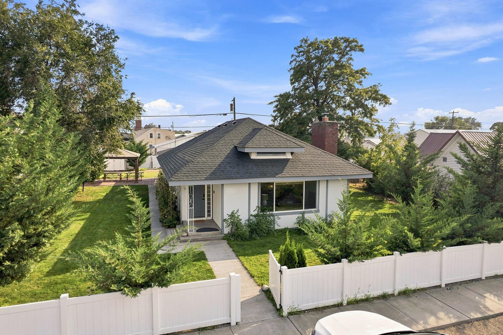 Elevated view of Sun Lake Retreat, showing the front lawn, covered porch, entry path and white fence.