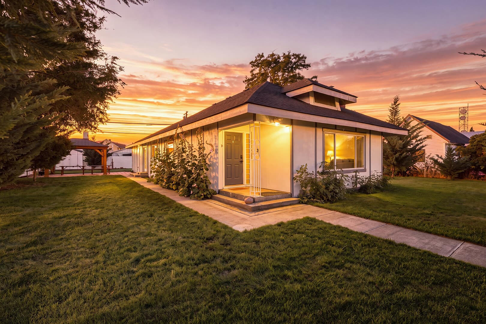 Sun Lake Retreat in Coulee City at twilight, with a lit front porch, lawn and colorful evening sky.