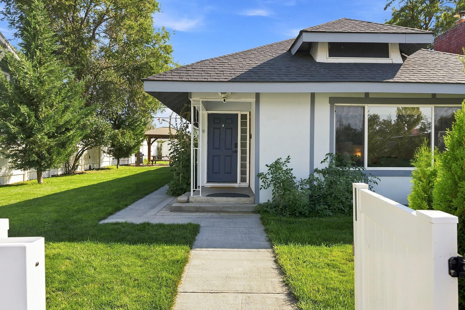 Straight walkway through the front lawn leading to the covered porch and blue entry door.