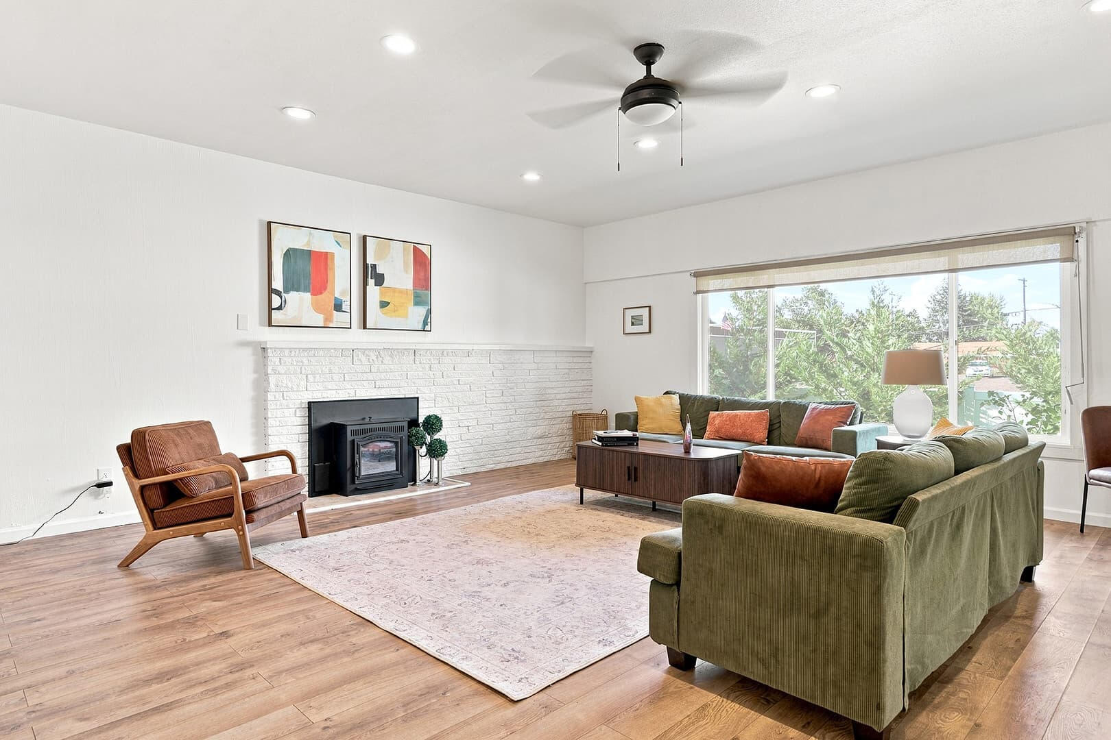 Bright living room with green sofas, a fireplace and large windows at Sun Lake Retreat.