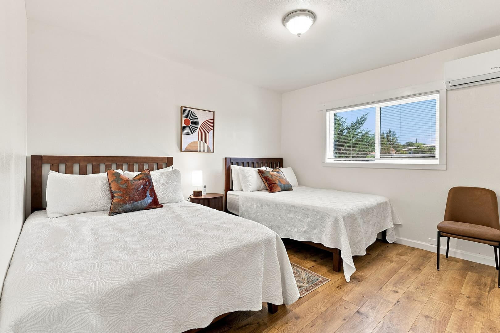 Two double beds with white bedding and wooden headboards, separated by a bedside table.
