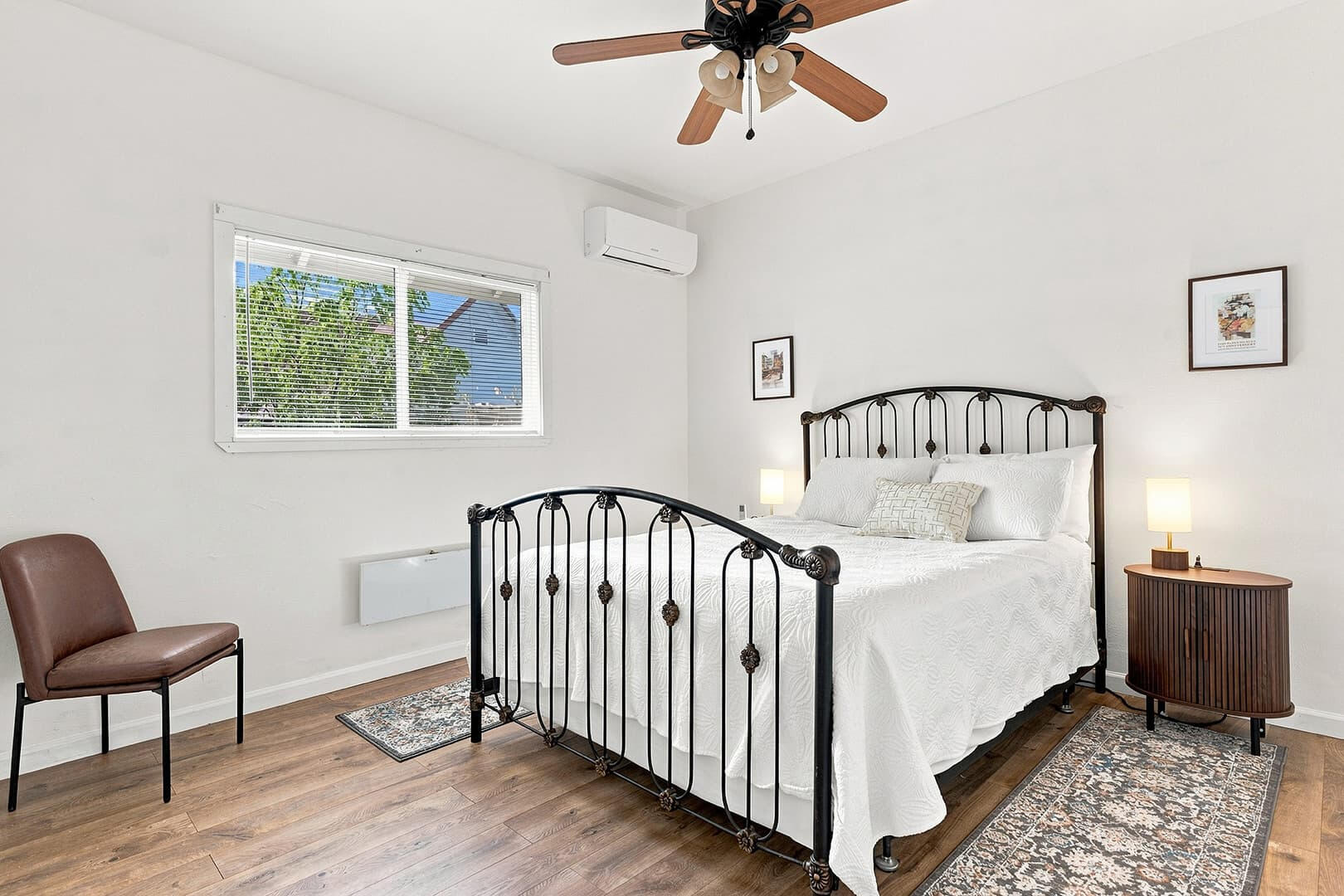 Queen bedroom with a black metal bed frame, white bedding and a ceiling fan.