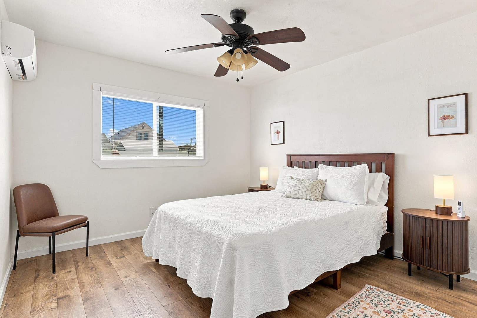 Queen bedroom with a wooden headboard, ceiling fan and window at Sun Lake Retreat.