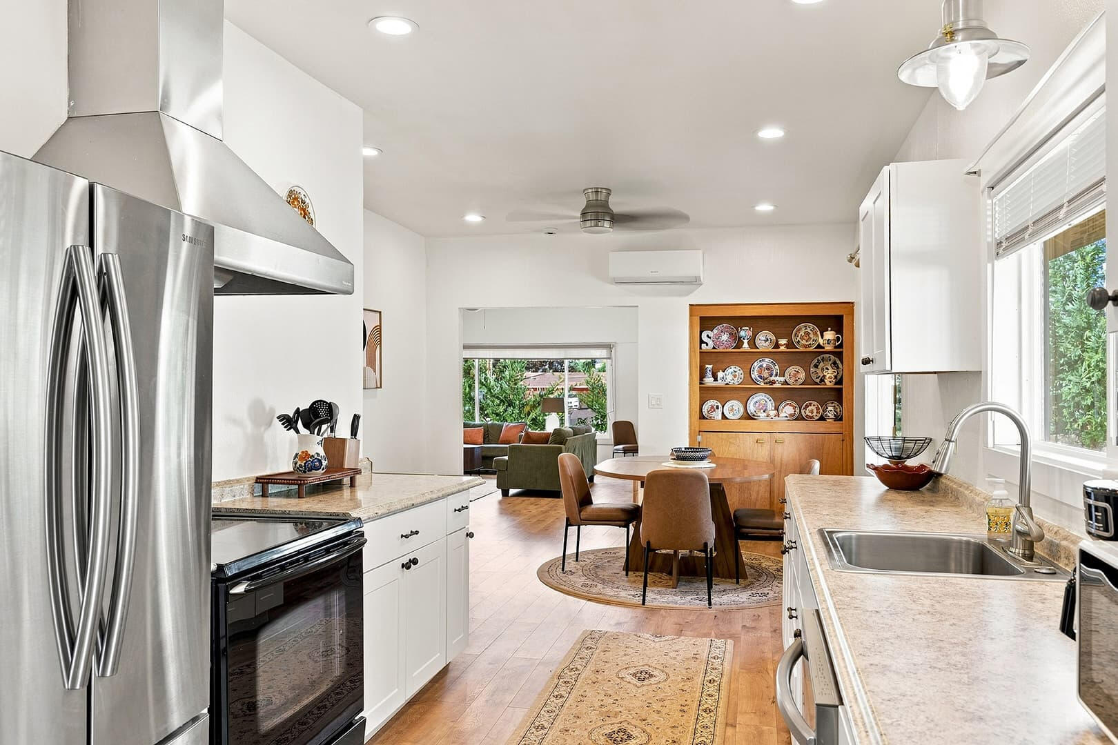 View through the kitchen toward the dining table, with a refrigerator and white cabinetry in the foreground.