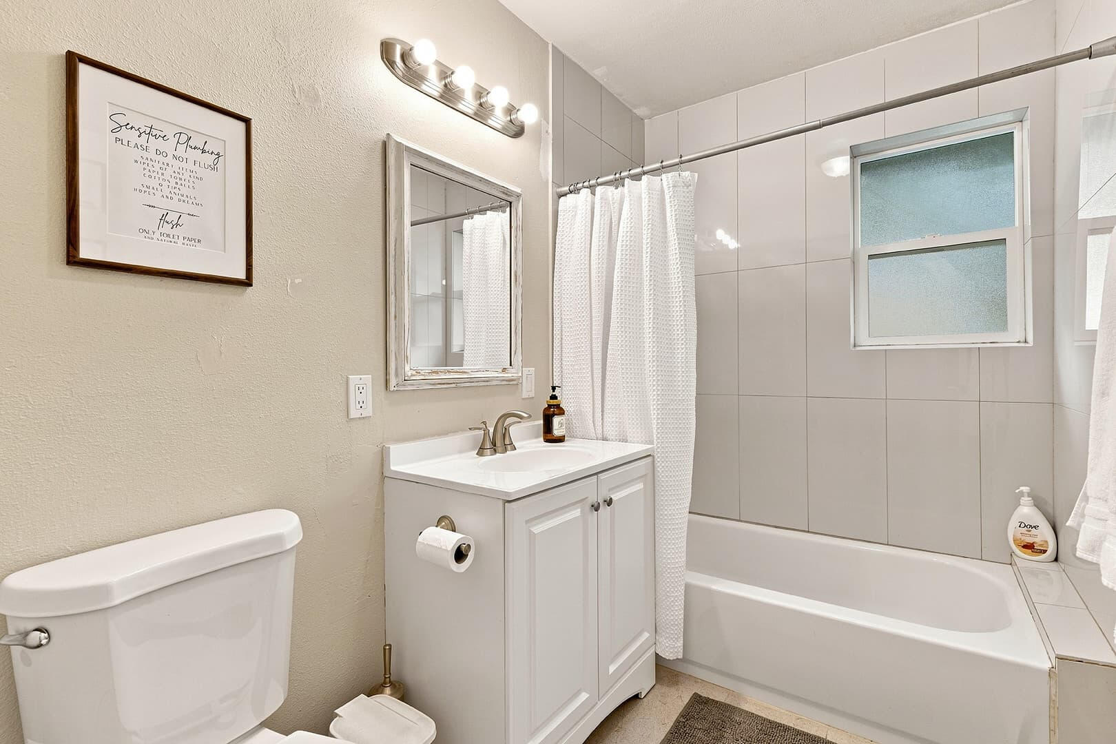 Bathroom with a white single-sink vanity and a bathtub with shower and curtain.