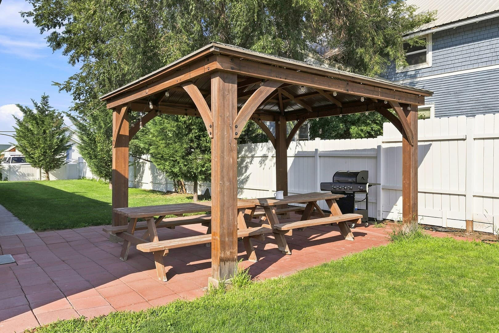 Covered patio with a wooden gazebo and picnic table beside the house at Sun Lake Retreat.