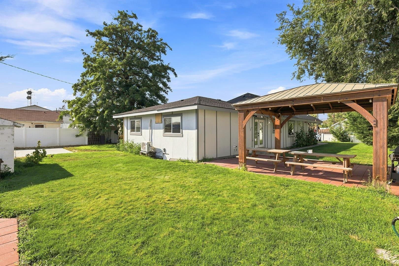 Backyard at Sun Lake Retreat with a green lawn, covered patio and white privacy fence.