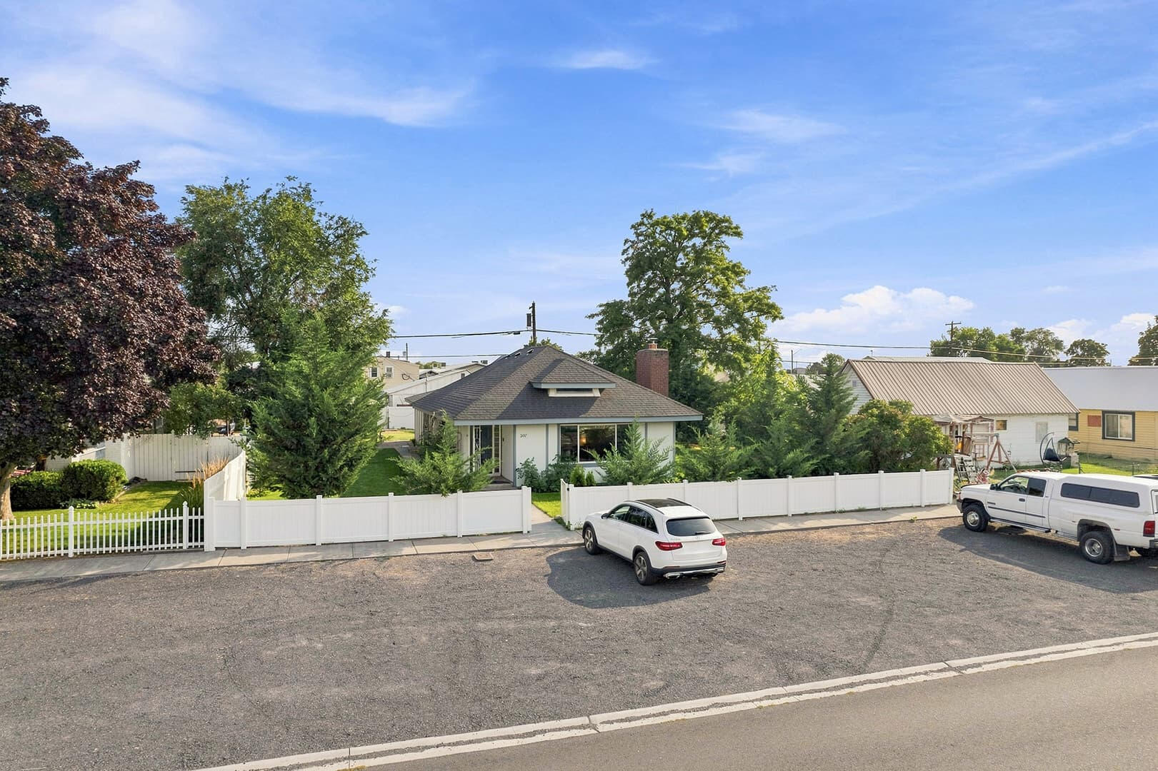 Elevated front view of Sun Lake Retreat, showing the porch, fence and vehicles in the parking area.